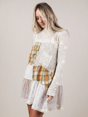 Woman wearing a layered dress with plaid and lace details on a plain background