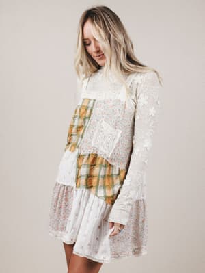 Woman wearing a layered dress with plaid and lace details on a plain background