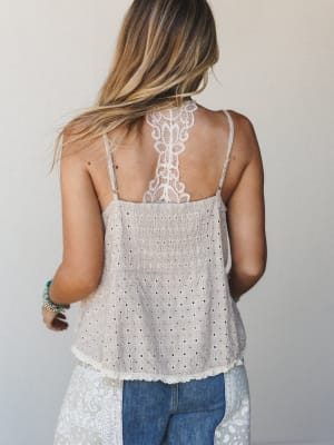 A back-facing shot of a model in a breezy eyelet cami with a standout lace racerback detail — the kind of top that looks just as good from behind as it does from the front, tucked into jeans or layered under a cardigan.