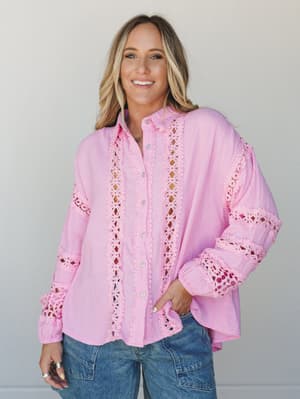 A candy pink gauze button-up with eyelet lace panel detailing worn open and relaxed over medium-wash cargo jeans — the kind of top that makes a Tuesday feel a little more intentional.