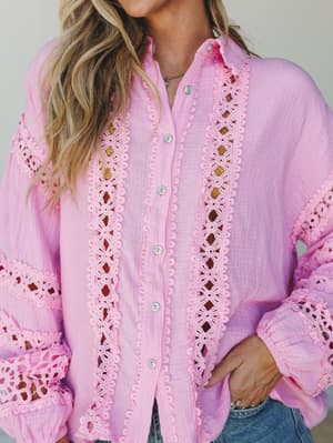 A soft candy pink button-up blouse in crinkle gauze fabric with intricate floral crochet lace trim running down the front placket and sleeves — the kind of top that does all the talking while you just enjoy your day.