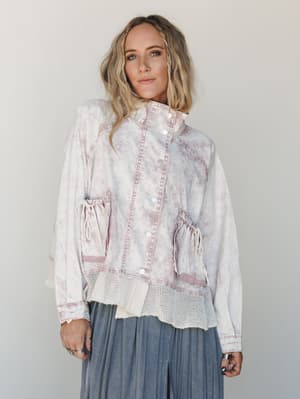 A soft, lived-in acid-wash jacket in dusty pink and cream layers over a slate blue pleated skirt — the kind of outfit that looks effortless but clearly wasn't an accident.