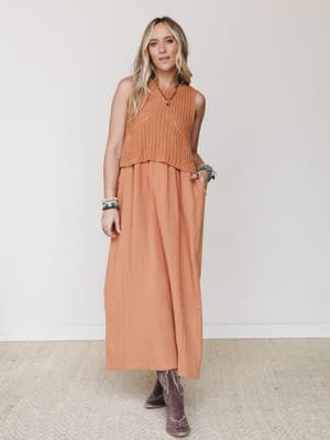 A tonal pumpkin-orange moment — a flowy maxi dress layered under a sleeveless crochet knit vest, styled with dusty western boots and stacked turquoise jewelry for that effortless boho-western crossover feel.