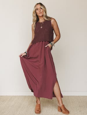 A flowy wine-toned maxi dress styled with a cropped open-knit sweater vest, wooden clogs, and layered boho jewelry — the kind of outfit that looks effortless but is clearly very much on purpose.