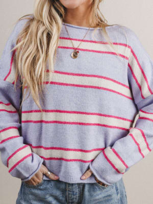 Woman wearing a striped sweater with purple, pink, and white colors on a neutral background