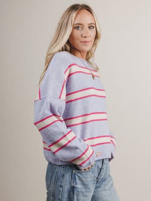 Woman wearing a striped sweater with a neutral background