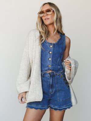 A breezy, put-together look anchored by an oversized cream knit cardigan layered over a denim two-piece set — the kind of outfit that looks effortless but clearly wasn't an accident.