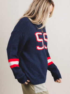 Person wearing a navy sweater with red and white accents on a plain background