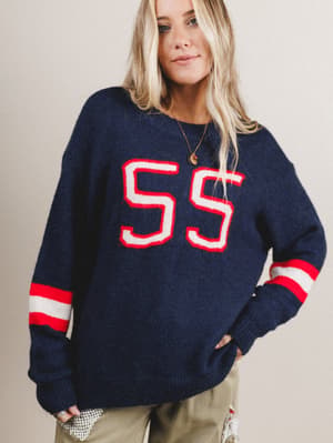 Woman wearing a navy sweater with red and white details