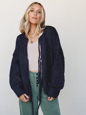 An oversized navy knit cardigan styled over a blush crop tank and sage corduroy wide-leg pants — the kind of effortless layering that looks like you thought about it for exactly the right amount of time.