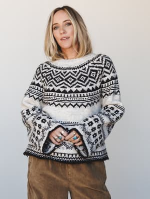 A cream and black Fair Isle knit sweater with dramatic bell sleeves, styled with olive corduroy pants and layered turquoise and silver rings — the kind of sweater that makes a Tuesday feel intentional.