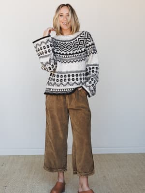An oversized Fair Isle sweater in cream and black paired with wide-leg cropped pants in a warm tobacco wash — the kind of outfit that looks effortless but is clearly on purpose.
