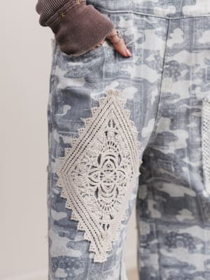 Close-up of a patterned fabric with lace detailing on a neutral background