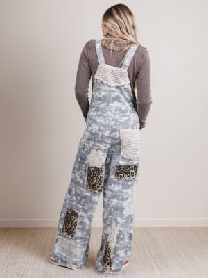 Person wearing a patchwork overalls with leopard print details on a plain background