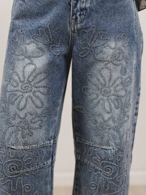Blue jeans with floral embroidery on a plain background