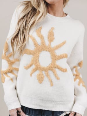 White sweater with beige sun design worn by a person