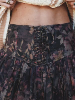 Close-up of a person wearing a floral skirt with a patterned top.