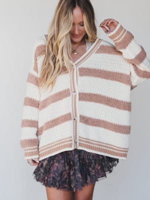 Woman wearing a striped sweater and floral skirt against a plain background