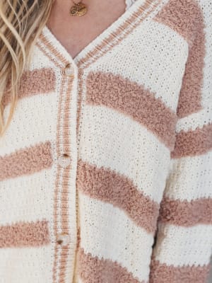 Close-up of a person wearing a white and brown striped cardigan.