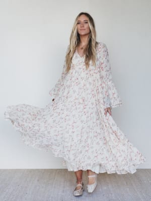 Woman wearing a white floral dress against a plain background