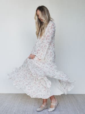 Woman wearing a long floral dress against a plain background