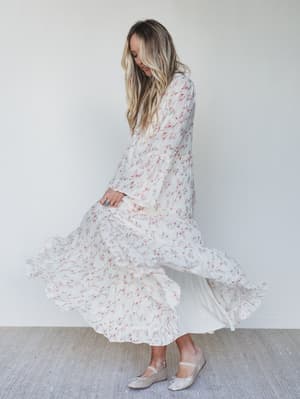 Woman wearing a long floral dress against a plain background