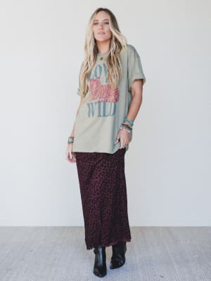 Woman wearing a graphic t-shirt and patterned skirt with a white background