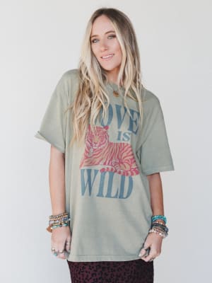 Woman wearing a graphic t-shirt with 'Love is Wild' text and design on a plain background