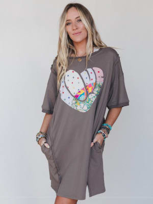 Woman wearing a gray t-shirt with a colorful heart design on a plain background