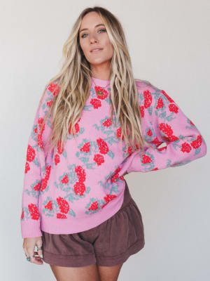 Woman wearing a pink floral sweatshirt and brown shorts against a white background