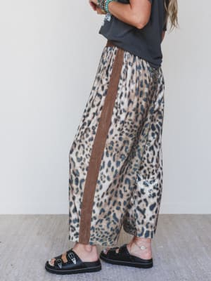 Person wearing leopard print pants with a brown stripe against a white background