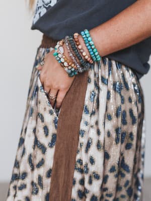 Person wearing multiple bracelets on a patterned skirt
