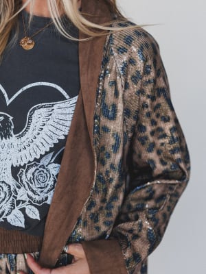 Close-up of a person wearing a leopard print cardigan over a black graphic t-shirt.