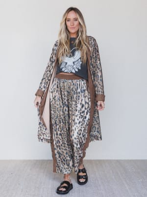 Woman wearing a leopard print outfit with a black top featuring an eagle design against a white background.