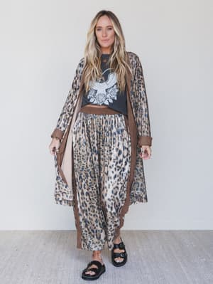 Woman wearing a leopard print outfit with a black top featuring an eagle design against a white background.