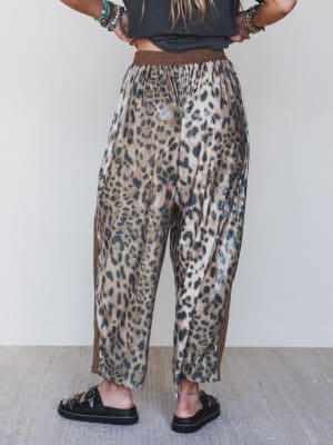 Person wearing leopard print pants with a plain background