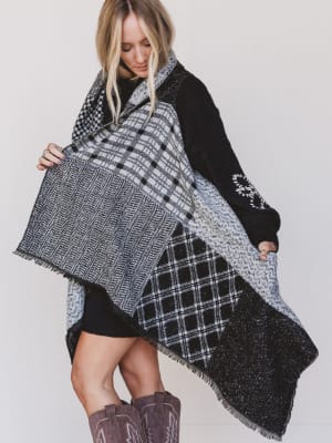 Woman wearing a black and white plaid poncho on a plain background