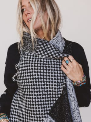 Woman wearing a black and white patterned scarf with a plain background