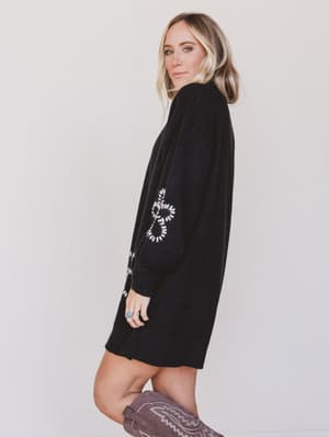 Woman wearing a black dress with a white design on a plain background