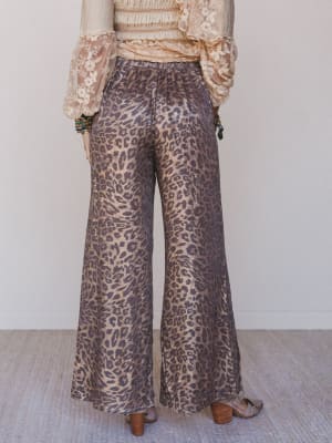 Person wearing leopard print pants with a plain background