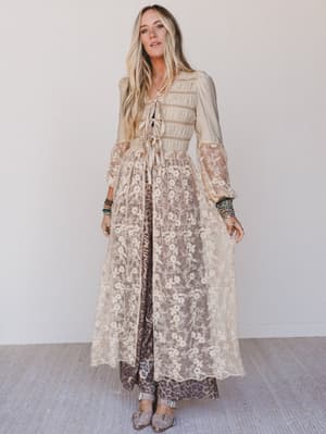 Woman wearing a long, floral-patterned duster with sheer sleeves against a white background