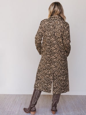 Person wearing a leopard print coat against a white wall