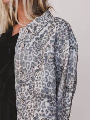 Leopard print denim jacket with studded details on a plain background
