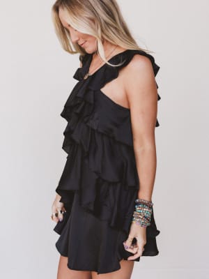 Woman wearing a black ruffled dress against a plain background