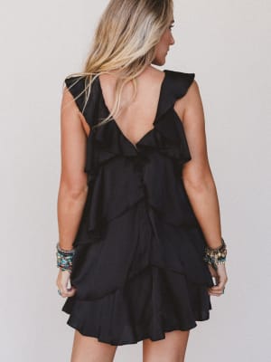 Black ruffled dress worn by a person on a plain background