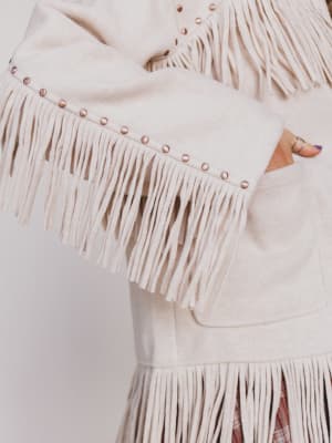 Beige fringe jackets with studded details on a plain background