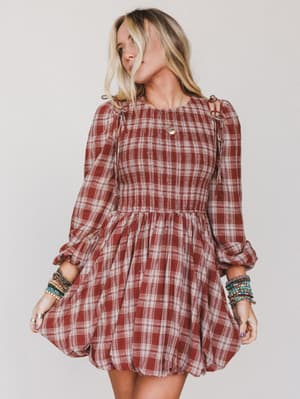 Woman wearing a red plaid dress with long sleeves against a plain background