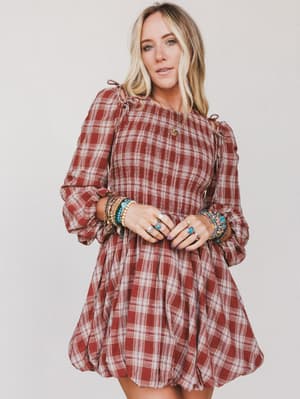 Woman wearing a red plaid dress with long sleeves on a plain background