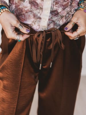 Brown pants being adjusted with a neutral background
