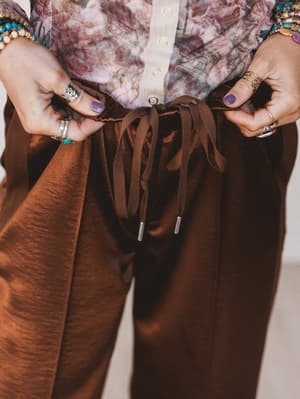 Brown pants being adjusted with a neutral background